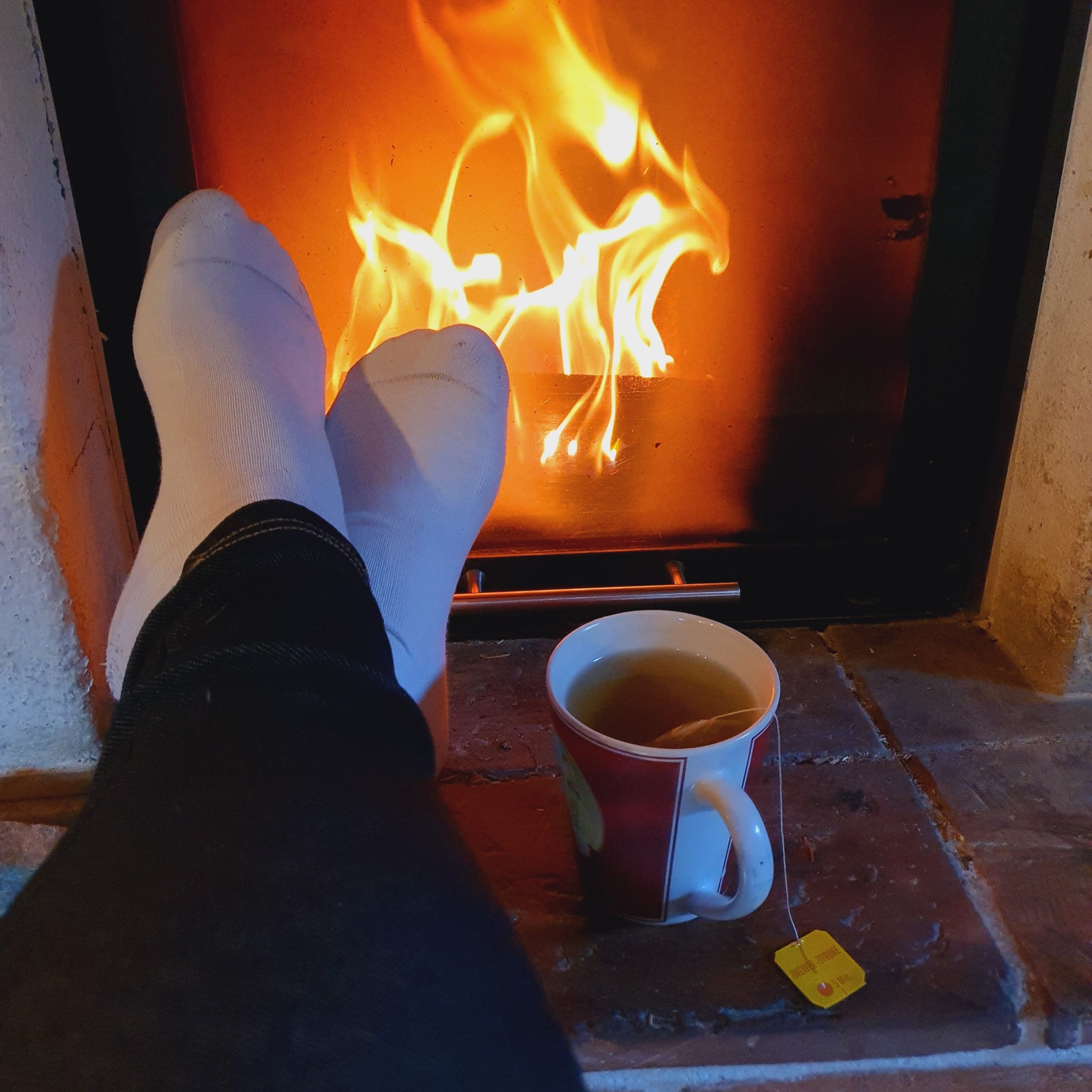 feet-in-front-of-a-fireplace-with-a-a-cup-of-tea feet-in-front-of-a-fireplace-with-a-a-cup-of-tea